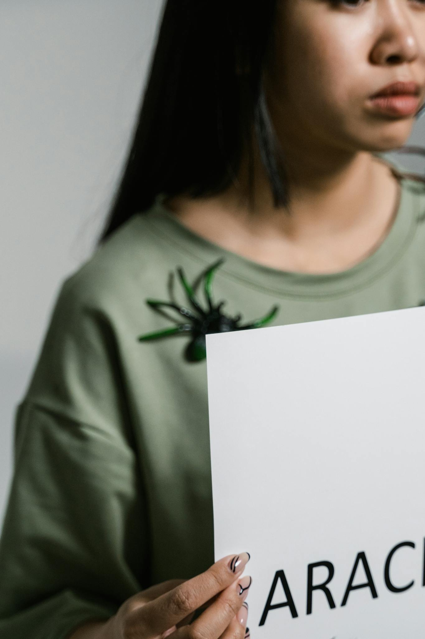 A woman holds a sign about arachnophobia, expressing fear and anxiety.